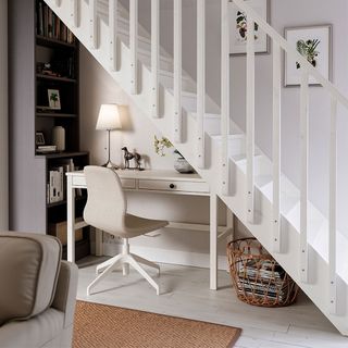 white desk and black bookshelf in under stairs storage and study area