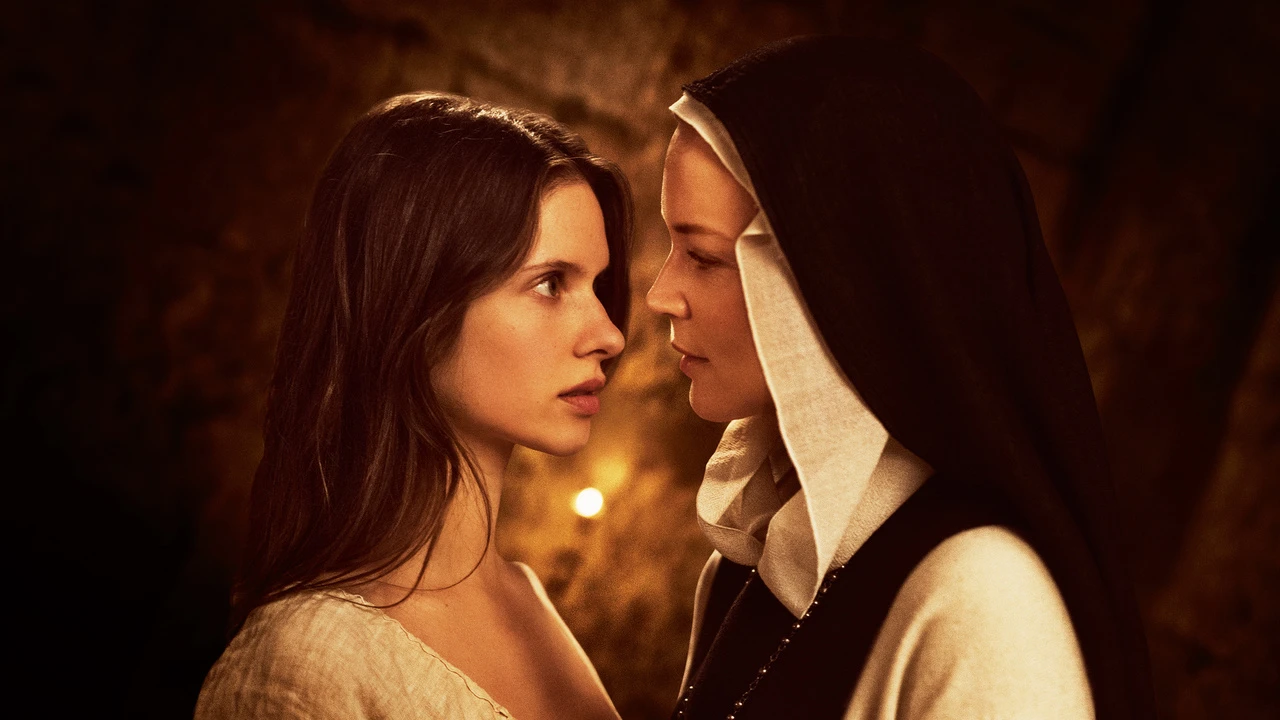 a nun and another woman in a nightgown lean in for a kiss in a still from the movie benedetta