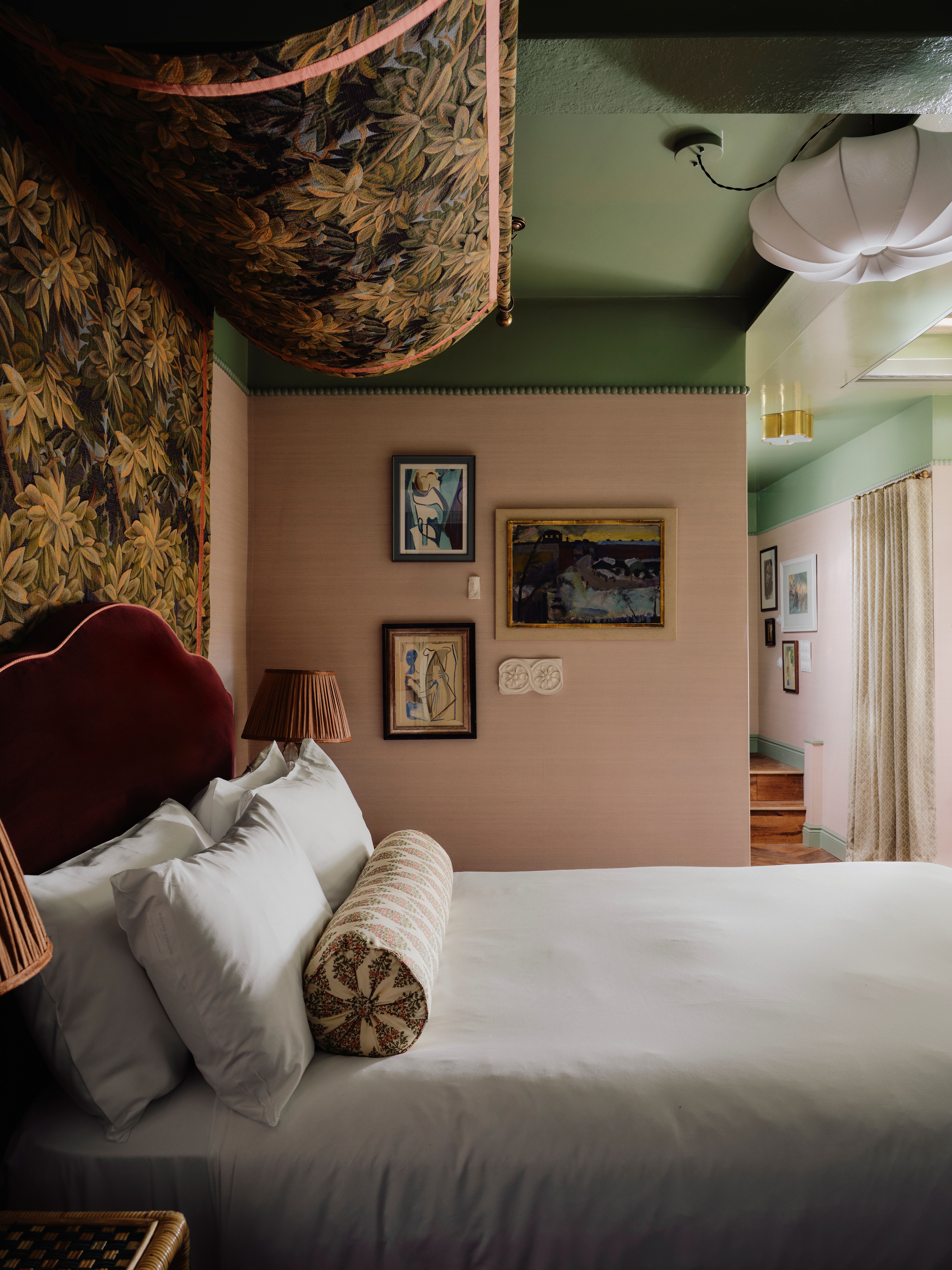 A maximalist hotel filled with tapestries, colorful tiling, velvety fabrics, artworks, and a pale green, pink, and red palette.
