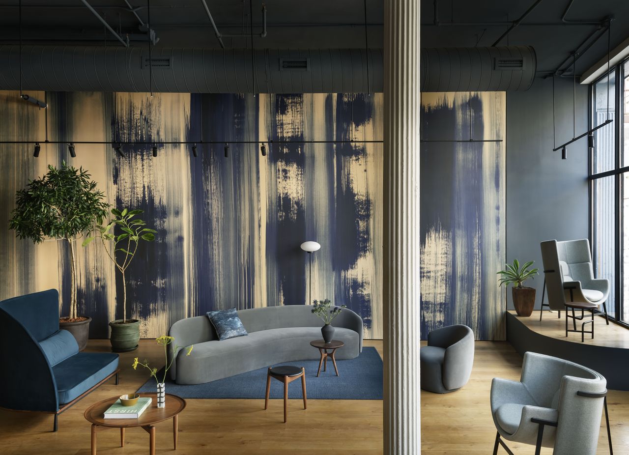 Wallpaper with hand-painted blue stripes with furniture display including grey sofa and freestanding floor lamp on a blue rug