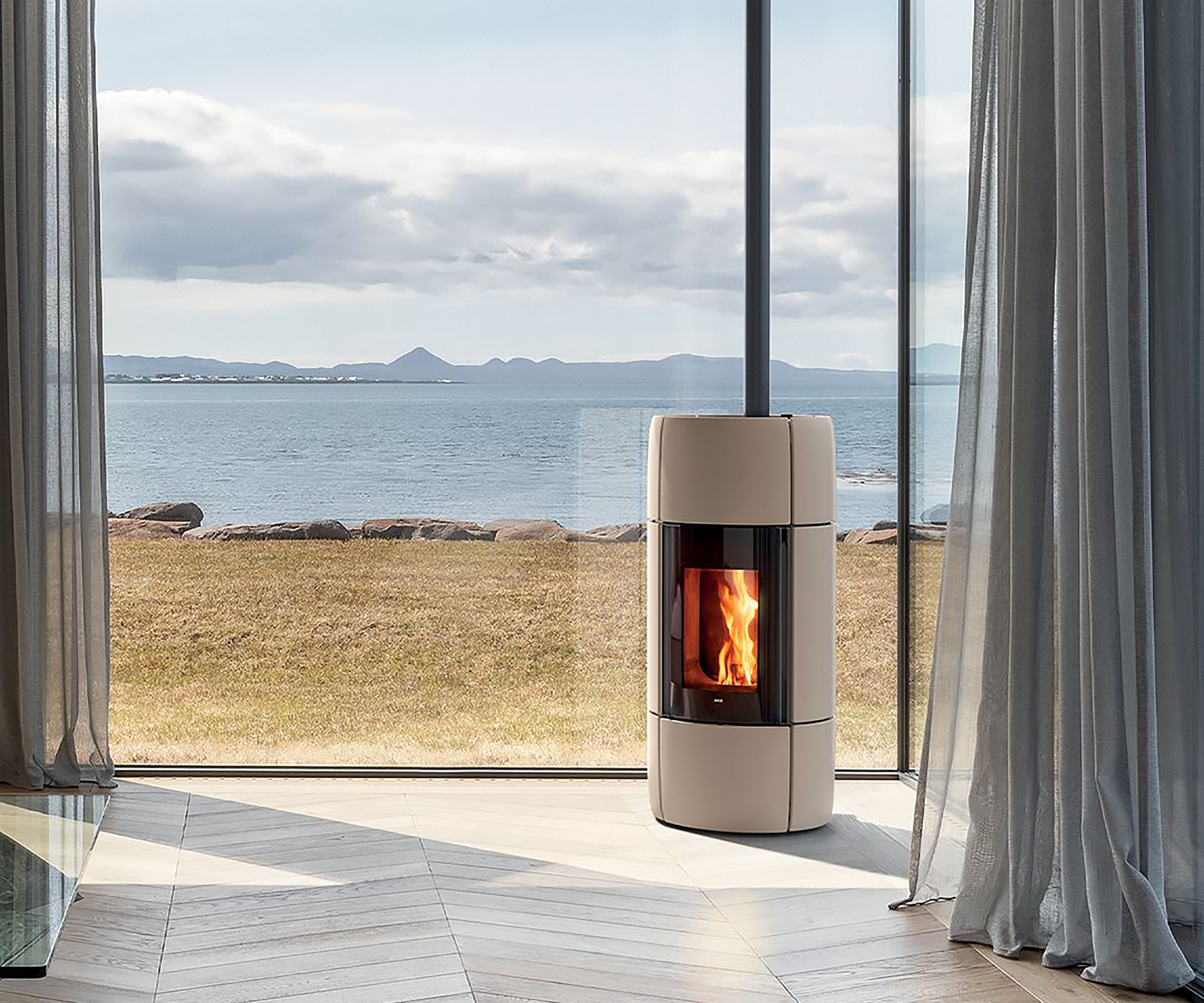 cream log burner in corner of glazed room with view out to sea