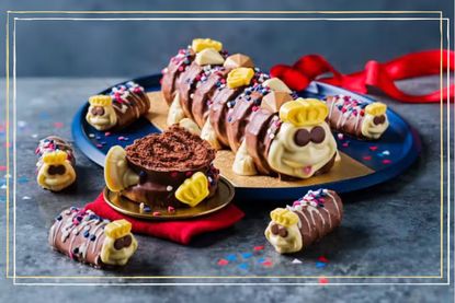 a lifestyle image showing King Colin the Caterpillar on a plate with mini Colin the Caterpillar cakes next to it