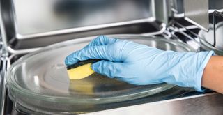 inside a microwave being cleaned with a soft sponge and dish soap showing how to clean a microwave