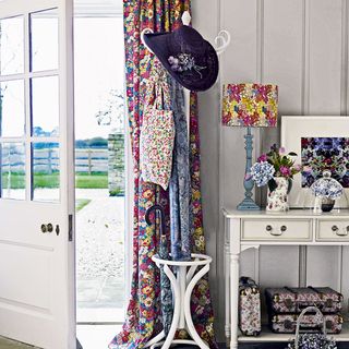 white room with floral curtains and table