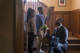 Alex Cross (Aldis Hodge, right) gets down on one knee and offers flowers to his family (from left: Juanita Jennings as Nana Mama, Melody Hurd as Janelle Cross, and Caleb Elijah as Damon Cross), in 'Cross.'