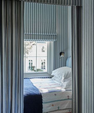 patterned drenched bed nook dressed in blue and white stripes with a matching window blind