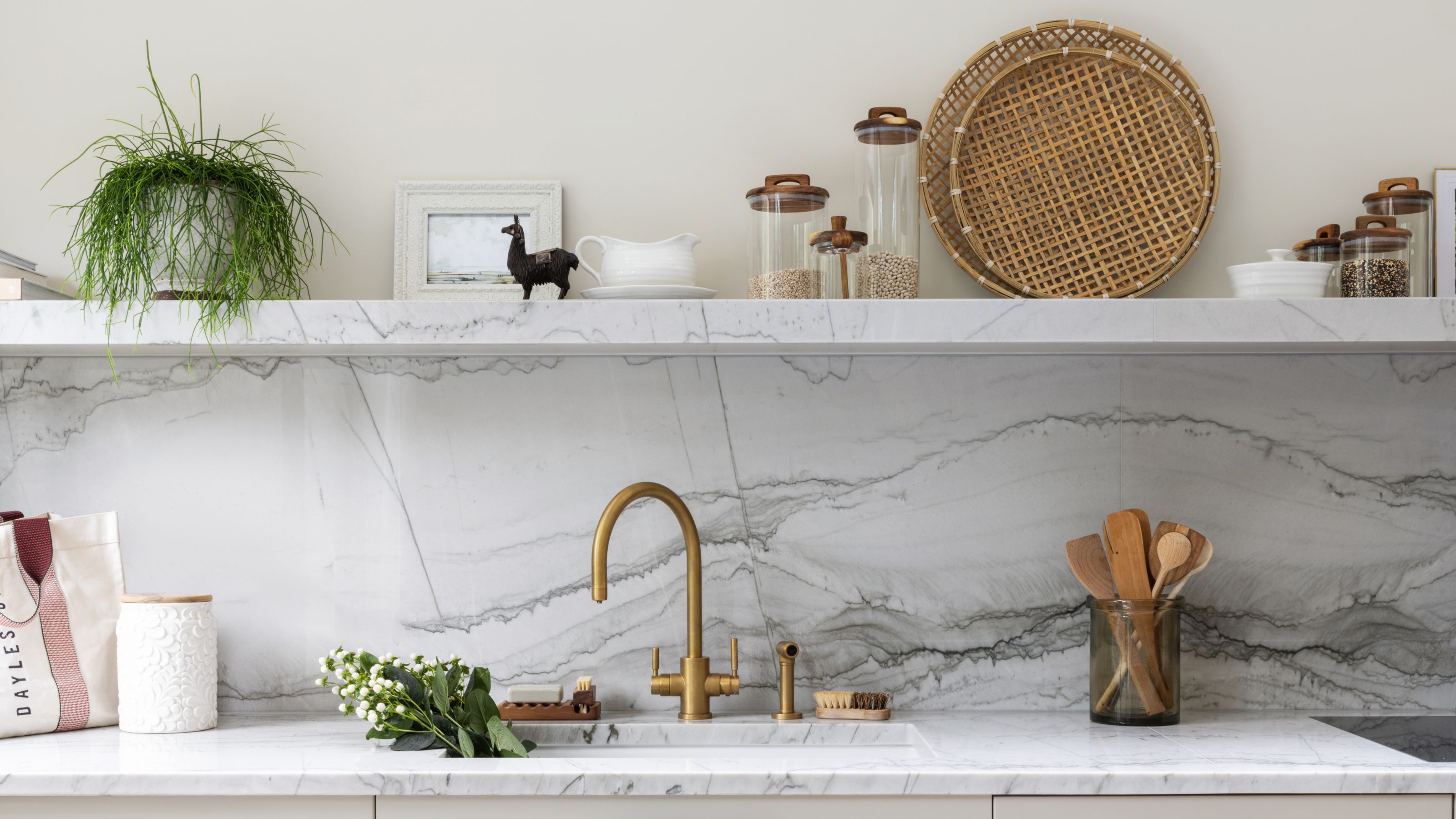 A kitchen with a stone wall and open shelving that has kitchen essentials on top of it 