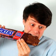 boy with blue tshirt eating gaint chocolate bar 