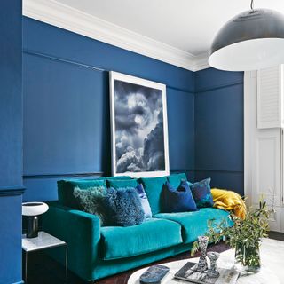 living room with blue wall and blue velvet sofa with cushion