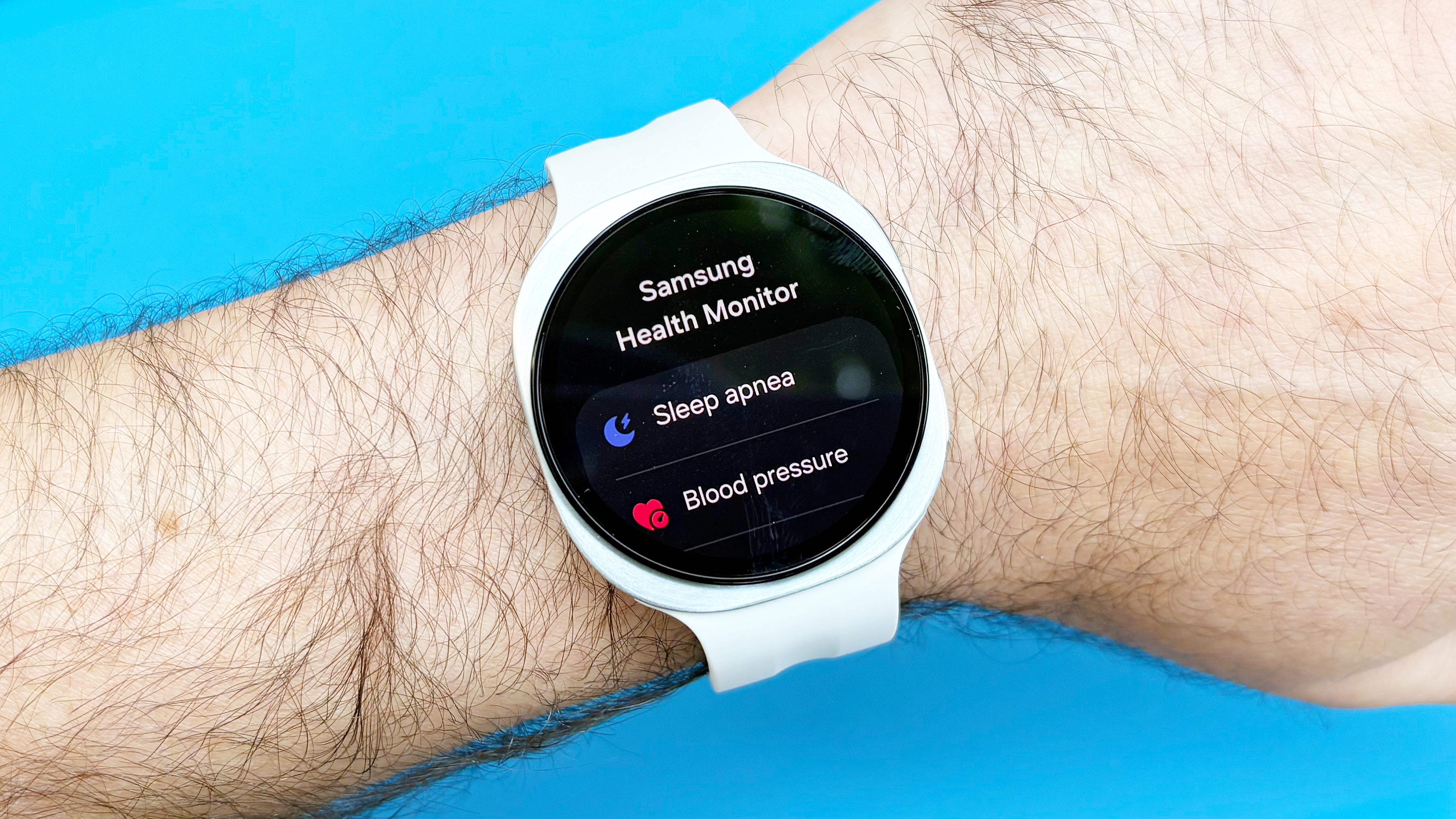 Close-up of the Samsung Galaxy Watch 9 on a user's wrist against a blue background
