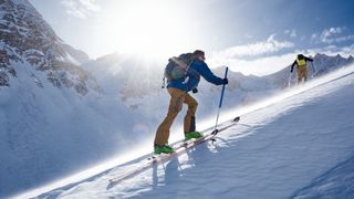 Two skiers make their way uphill using AT skis and bindings