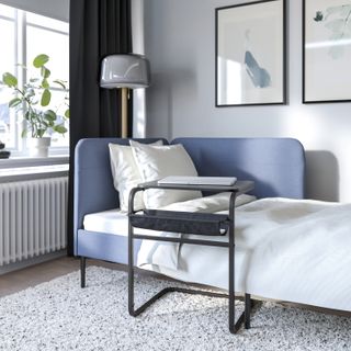 A bedroom with a blue day bed and a couch desk