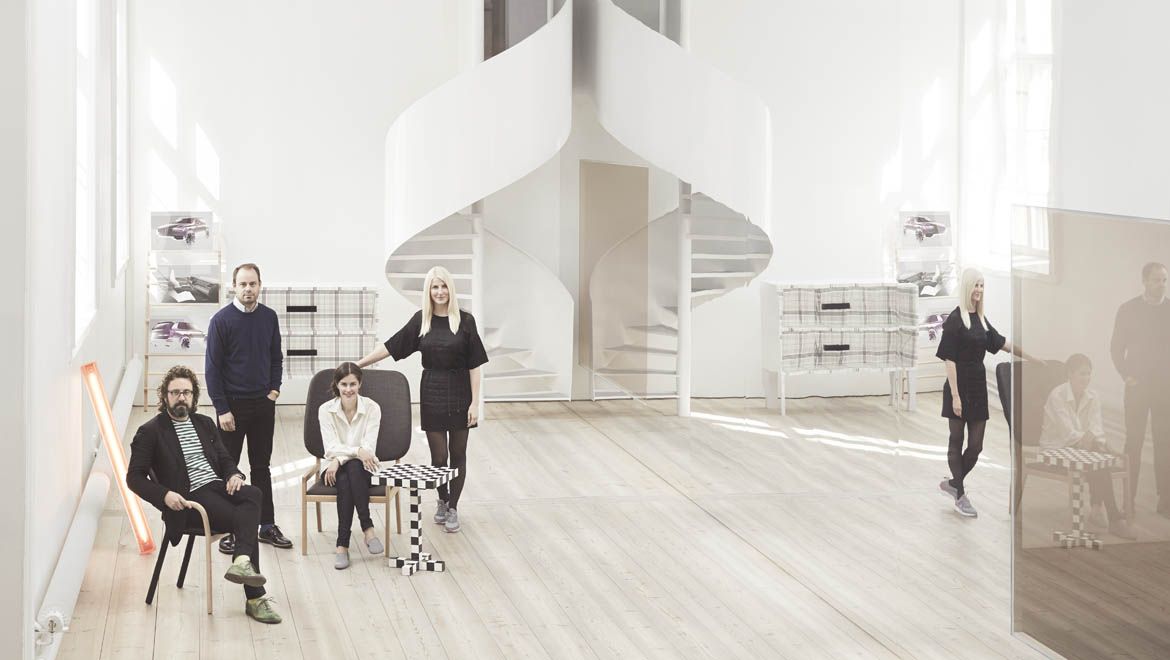 Four people in a mirrored room with a white spiral staircase