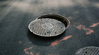 A close up of a circular manhole cover partially removed. 