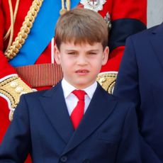 Prince Louis wears a navy suit, white shirt, and red tie at Trooping the Colour 2025