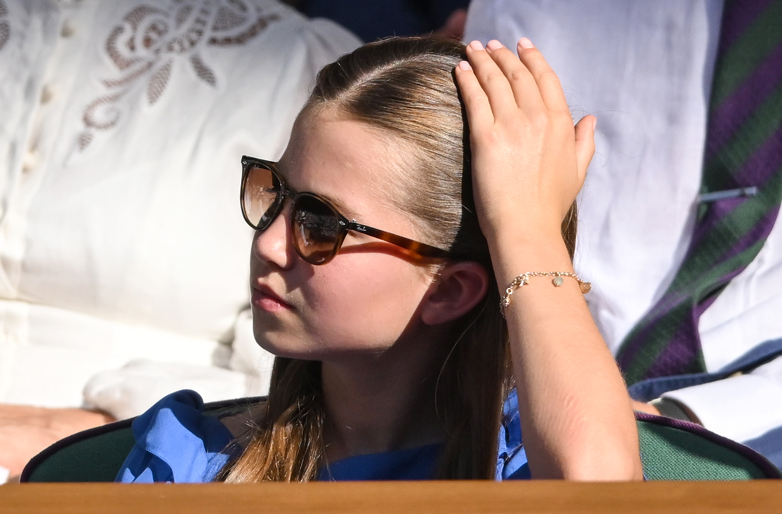 Princess Charlotte wearing sunglasses and putting her hand against her head at Wimbledon
