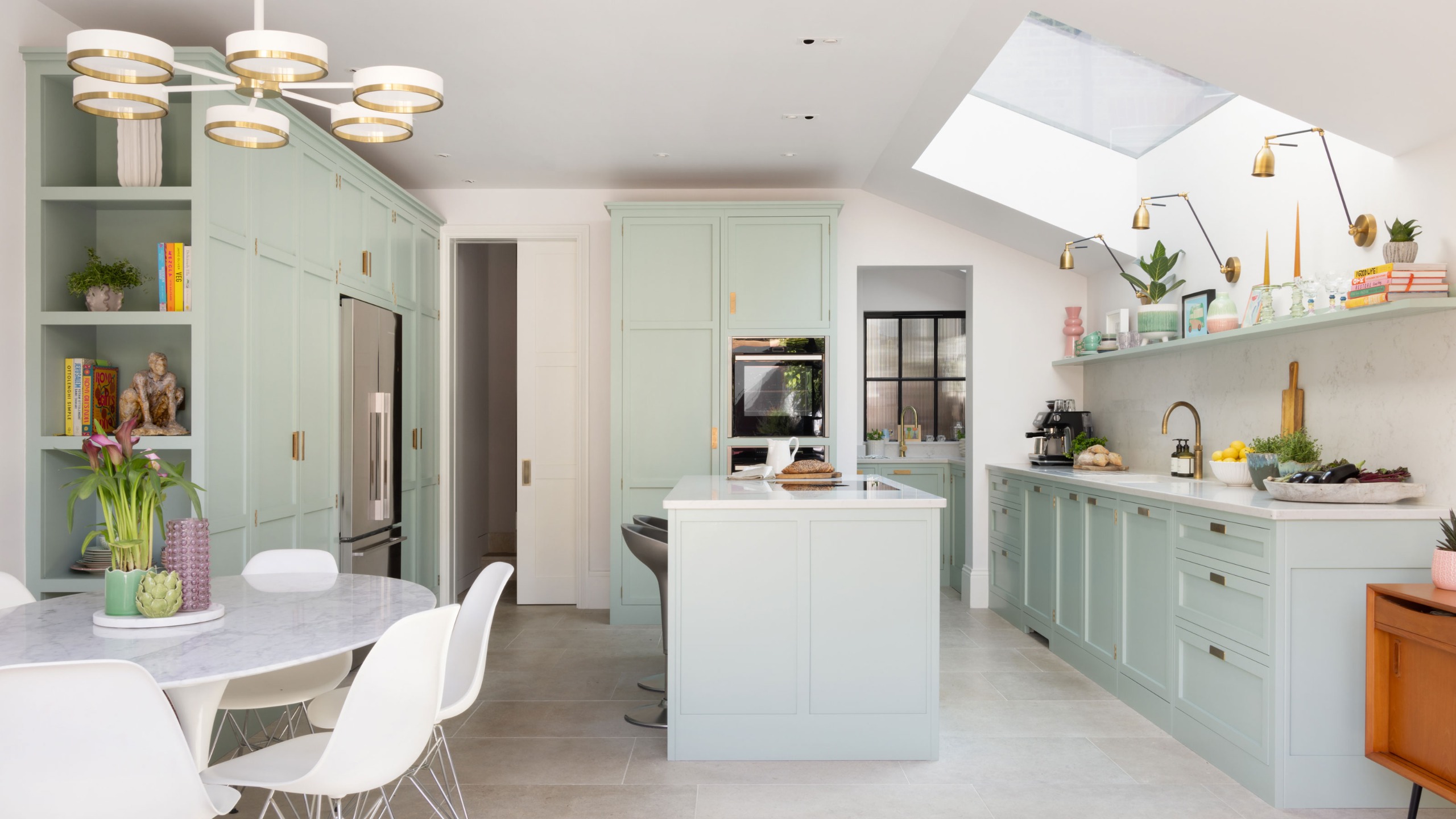 pale blue Shaker kitchen with large rooflight and kitchen island and white circular dining table