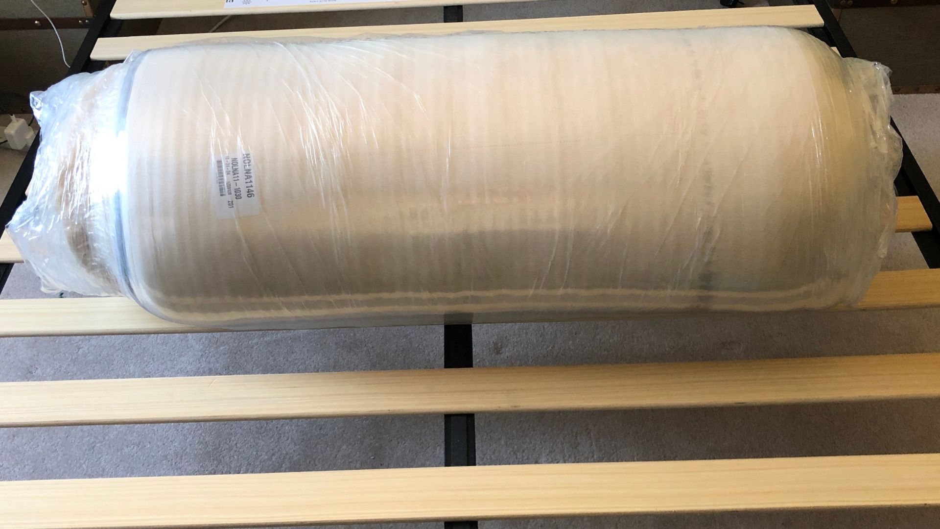 The Nolah Natural 11 Mattress unboxed and wrapped in plastic on the bed frame.