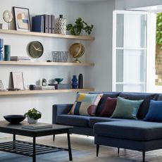 A living room with three long floating shelves and a dark blue sofa