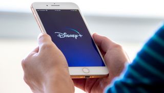 Disney Plus logo shown on a mobile phone that&#039;s held by two hands