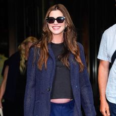 Anne Hathaway wears navy trouser with a black t-shirt, sparkly blazer and mesh ballet flats.