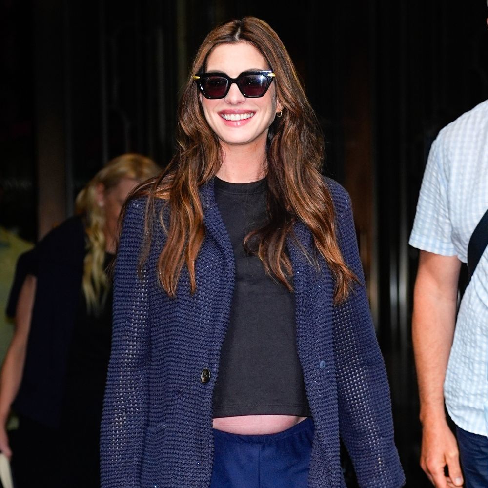 Anne Hathaway wears navy trouser with a black t-shirt, sparkly blazer and mesh ballet flats.