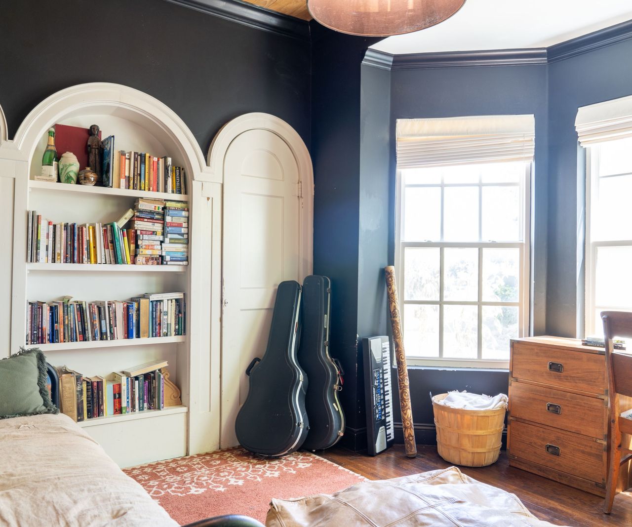 Black room with large windows, arched shelves and wood desk