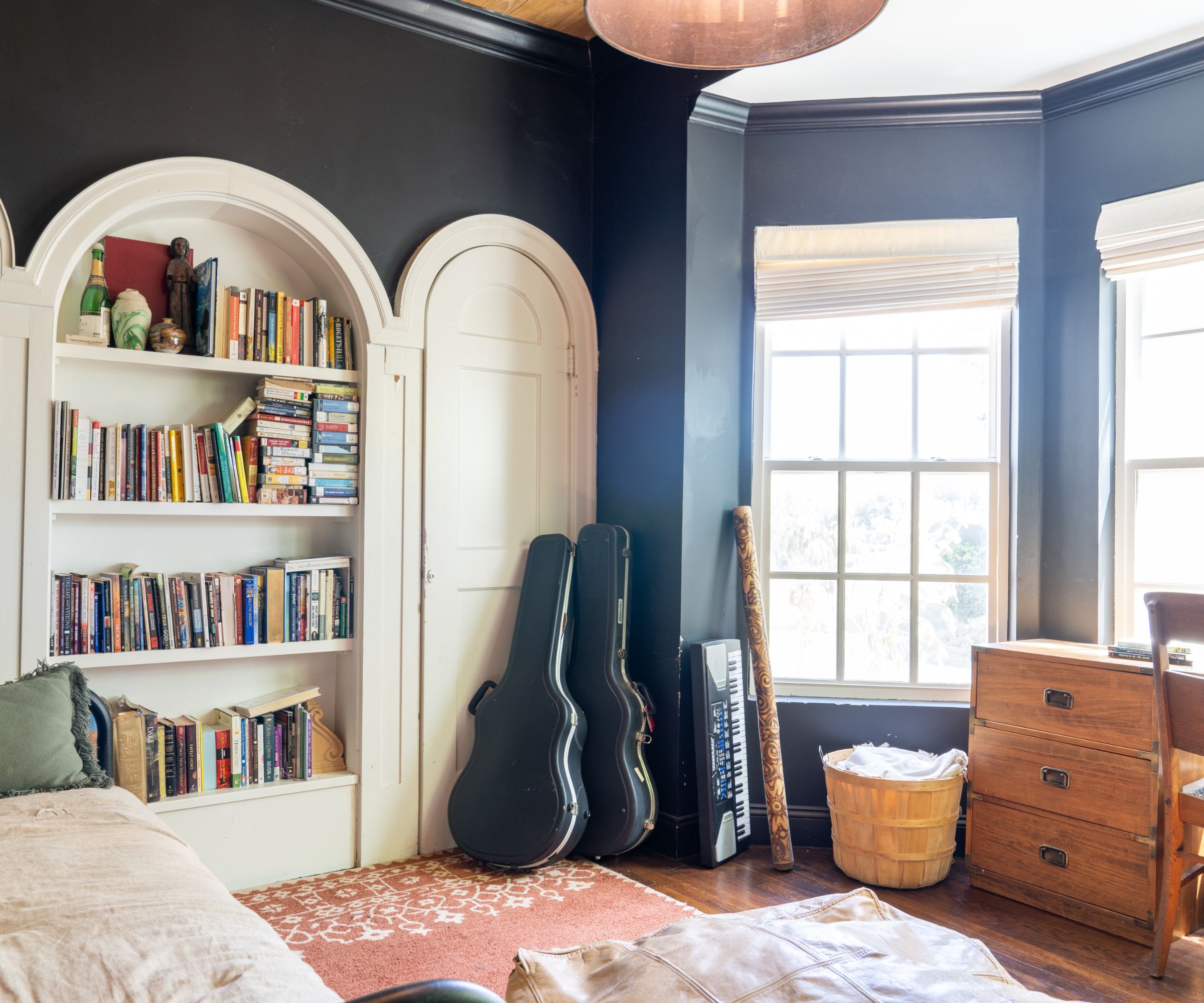 Black room with large windows, arched shelves and wood desk