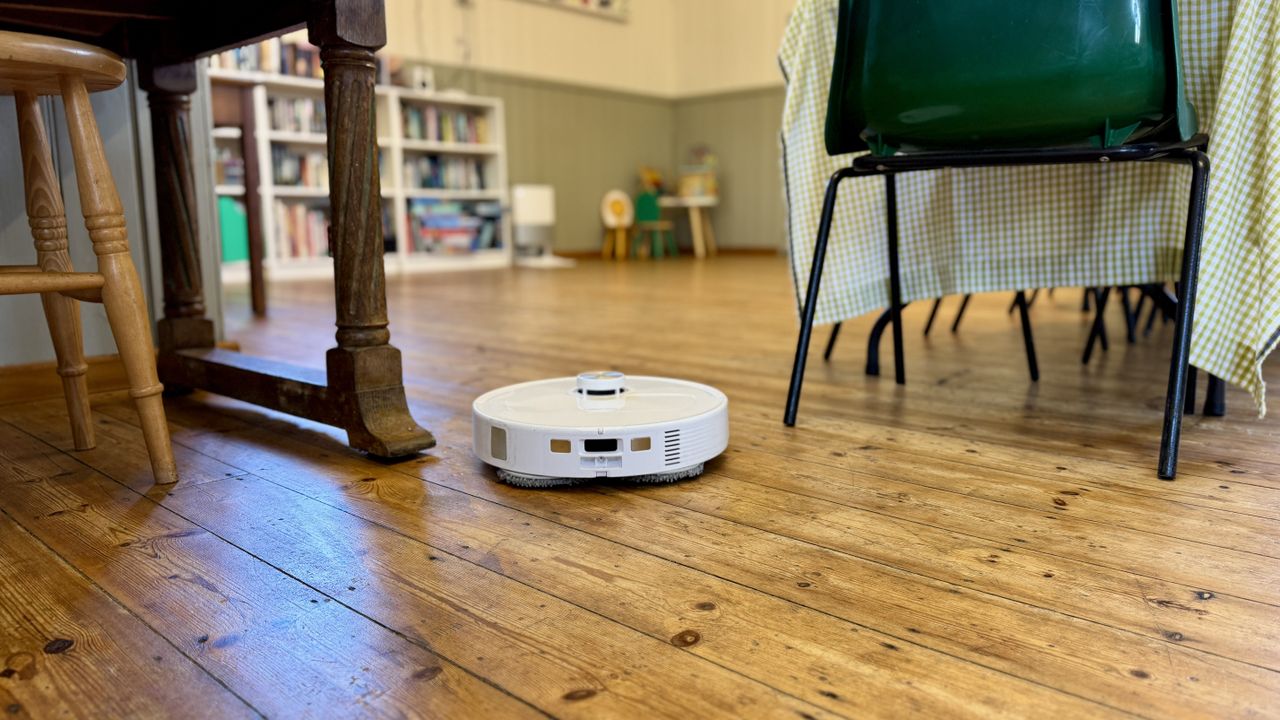 Roborock Qrevo Master robot vacuum navigating furniture in a village hall