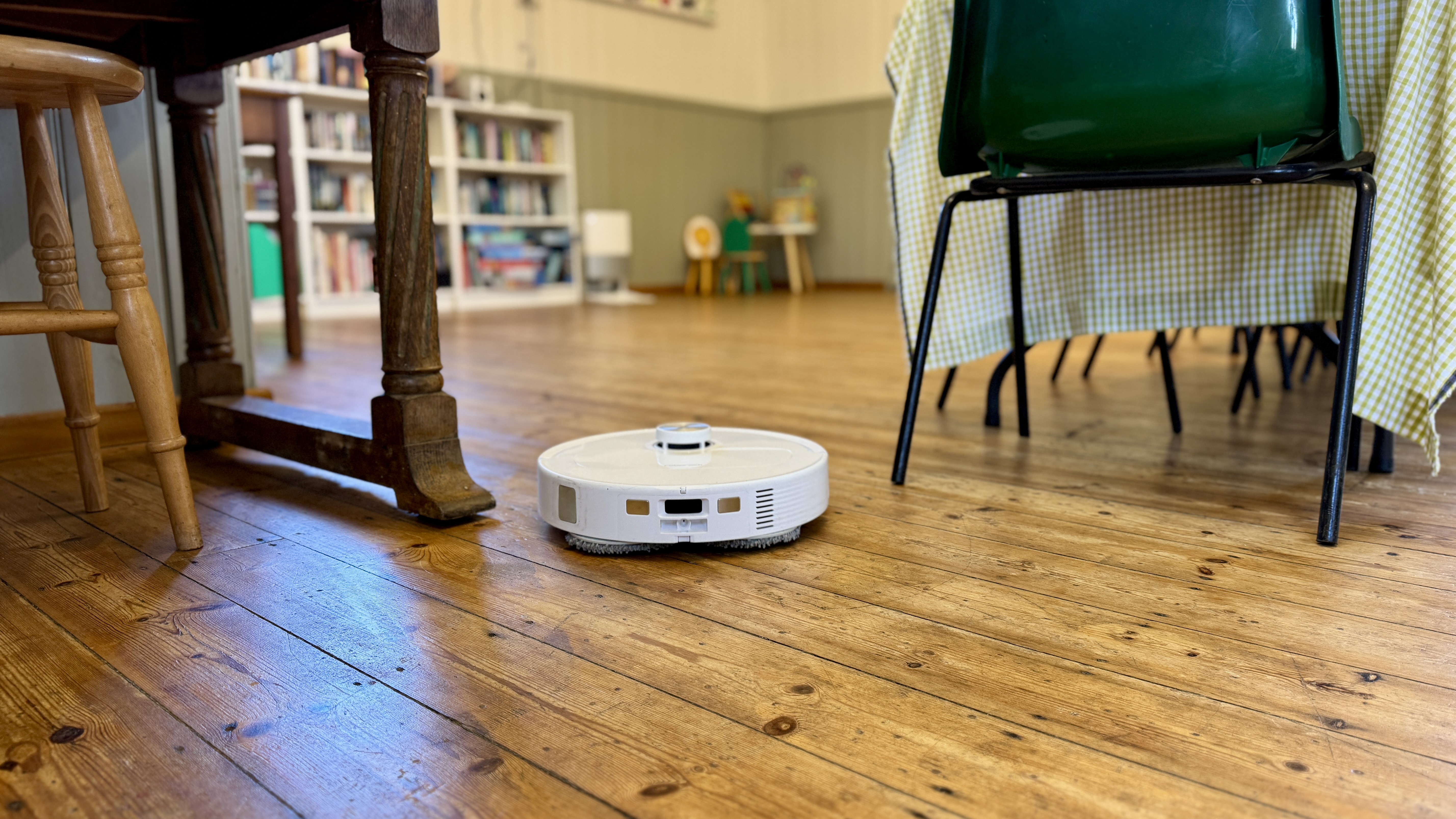 Roborock Qrevo Master robot vacuum navigating furniture in a village hall 