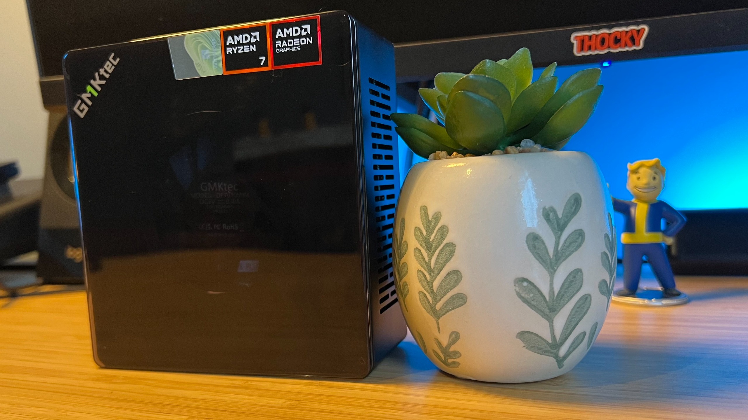 GMKTec K8 Plus mini PC standing upright on a wooden desk