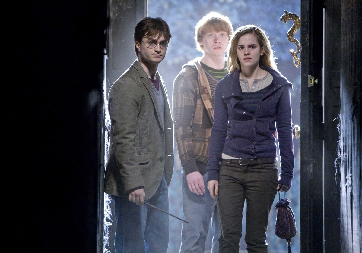 Daniel Radcliff, Rupert Grint and Emma Watson stand in a doorway