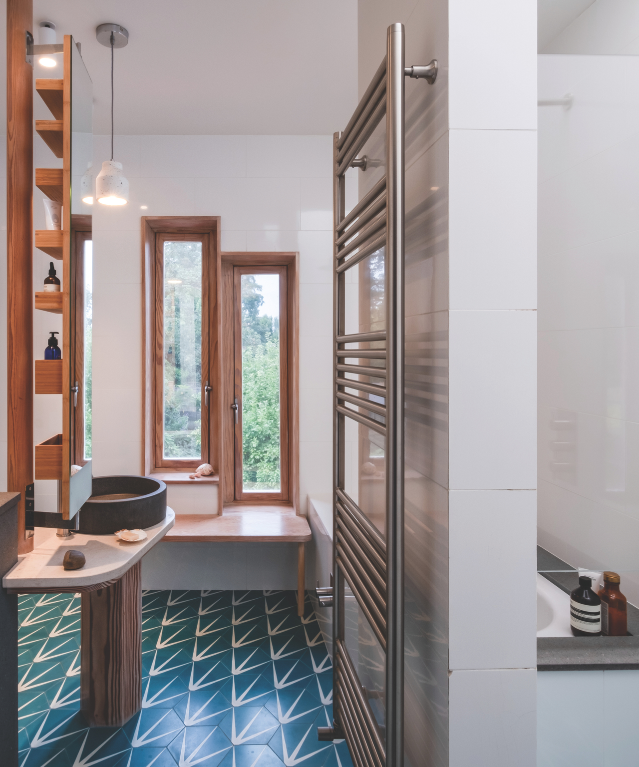 Room with blue and white patterned tiles, wooden windows at the far end and a sink to left hand side