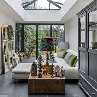 A conservatory living room with large sofa and artwork