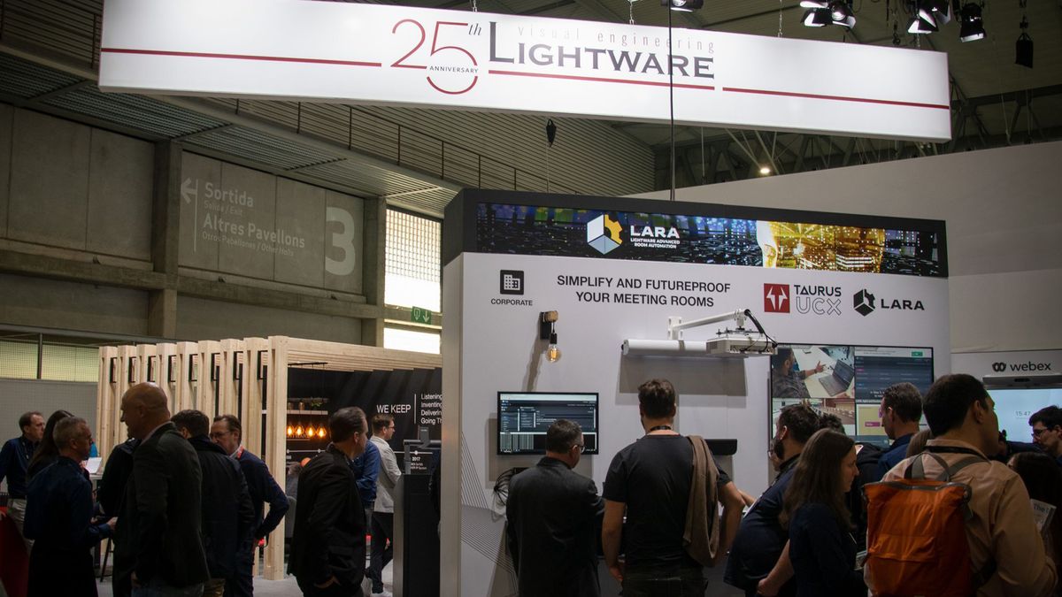 A group around Lightware&#039;s booth with a sign celebrating its 25th anniversary.