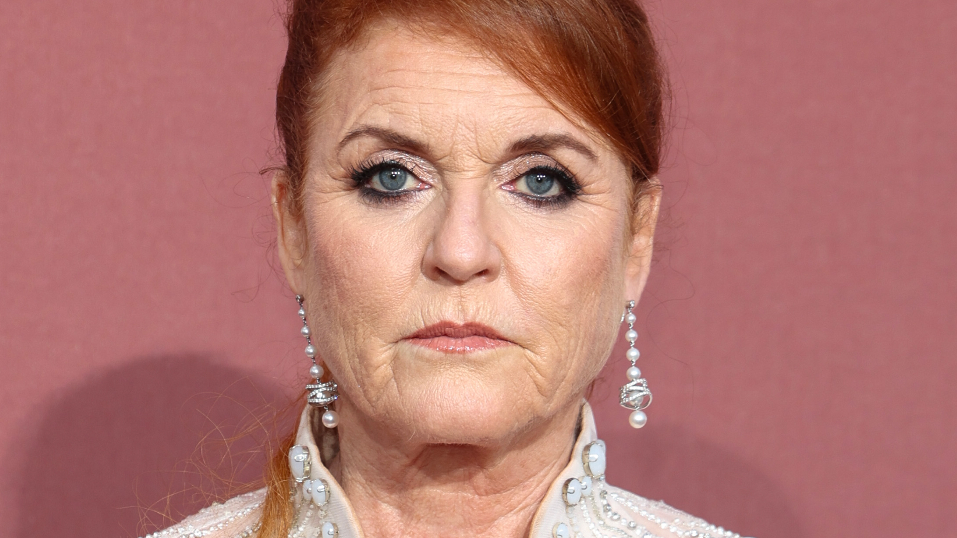 Sarah Ferguson looks worried while wearing diamond drop earrings and a white sheer dress adorned with crystals