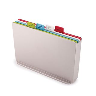 A silver chopping board holder with four colorful chopping boards within it