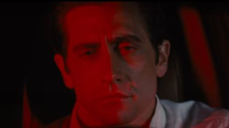 Jake Gyllenhaal bathed in red behind a steering wheel in Nocturnal Animals