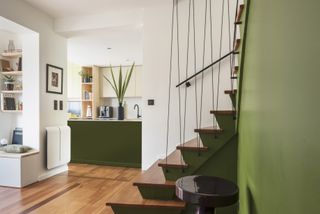 green painted modern staircase with matching green kitchen island, wooden floor and treads, white walls