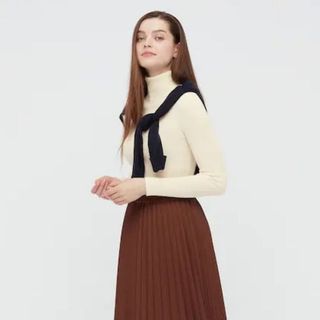 Cream roll neck paired with brown pleated skirt shown on model
