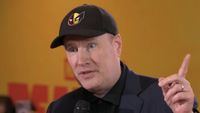 Kevin Feige wearing Deadpool and Wolverine hat and pointing upwards during interview