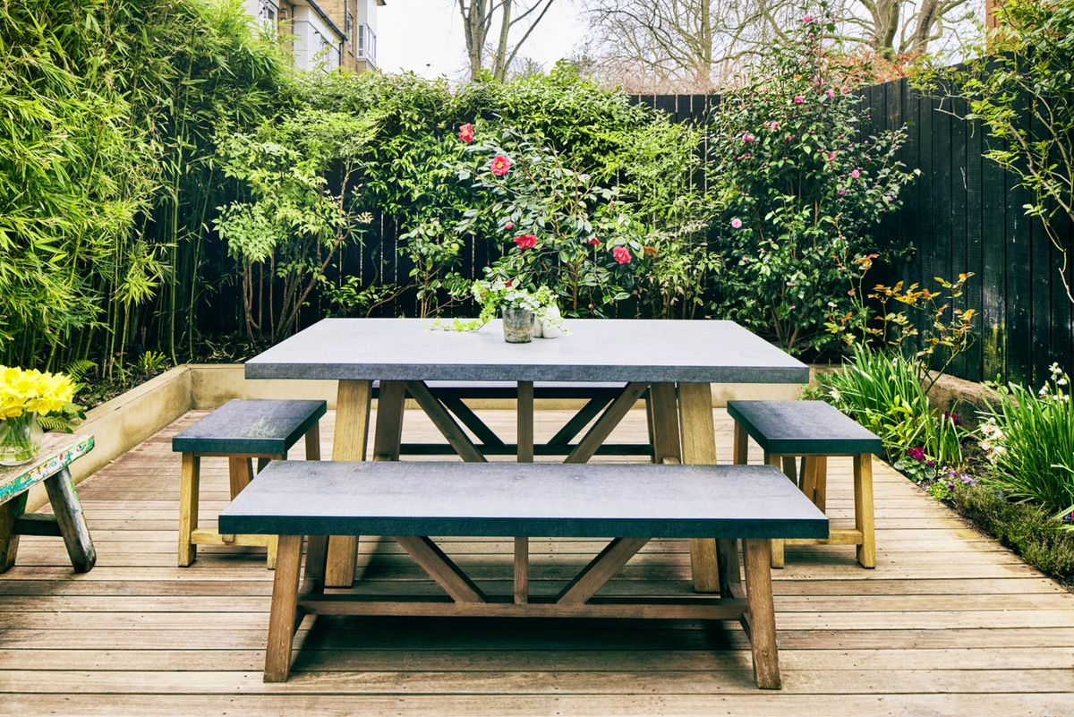 The garden has a decked area with plants in separated boundaries where plants such as climbing roses and bamboo reside