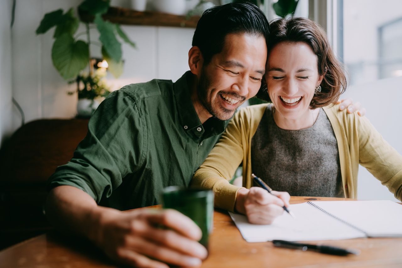 A young couple writes in a notebook.