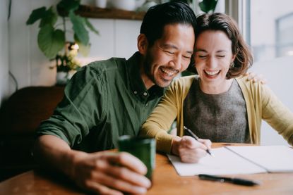 A young couple writes in a notebook.