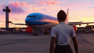 A pilot looks out over an airplane at sunset