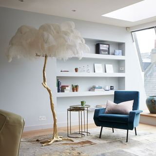 living room with white shelves on wall and feather lamp