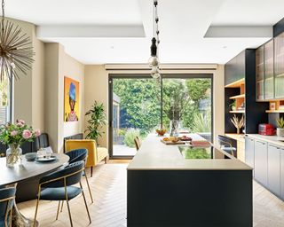 Modern, open-plan kitchen with island, floor to ceiling windows, dining seating area, work desk area