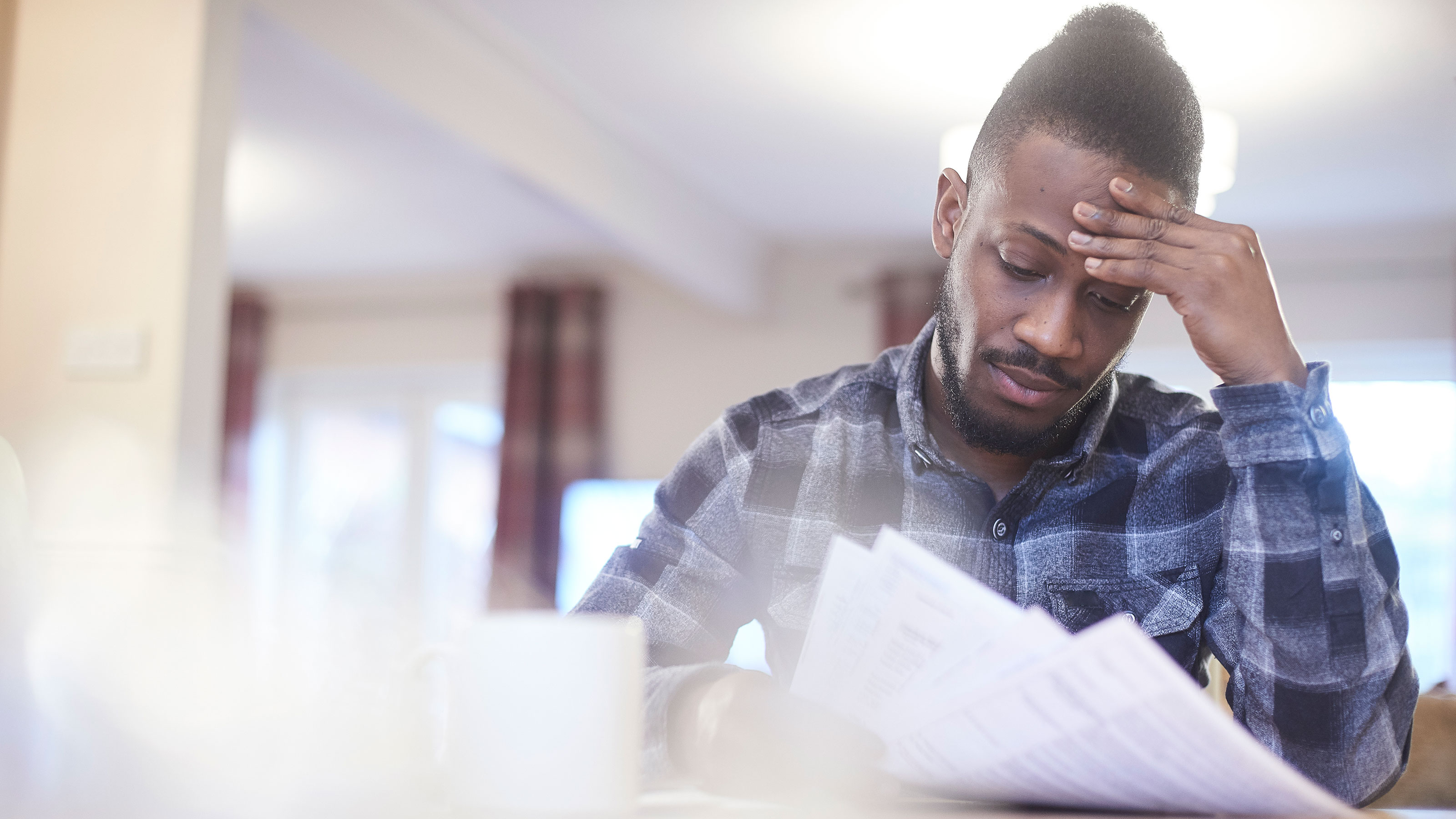 Worried young male reading through bank statements