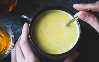 A woman stirring a cup of golden milk