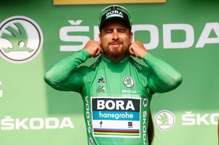 Peter Sagan gingerly pulls on the green jersey after stage 18 at the Tour de France